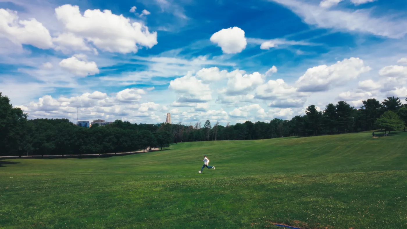 Ben running across a green field under an open summer sky