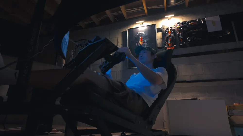 Ben at the sim rig, lit by the racing screen
